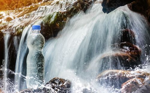 Plastic water bottle standing near waterfall.