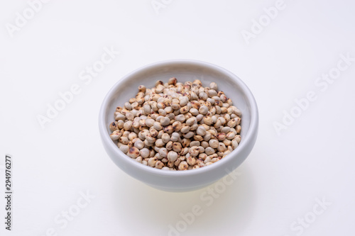 Uncooked raw Sorghum (also known as sorgo) in a white bowl, isolated on white background