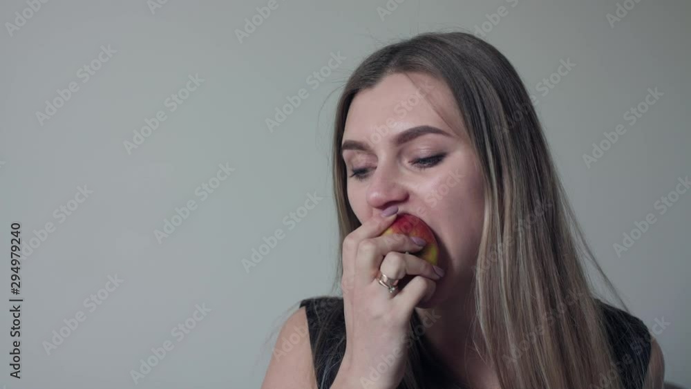 Portrait of a pregnant young woman sitting at sofa and eating an apple Portrait of a pregnant young woman sitting at sofa and eating an apple