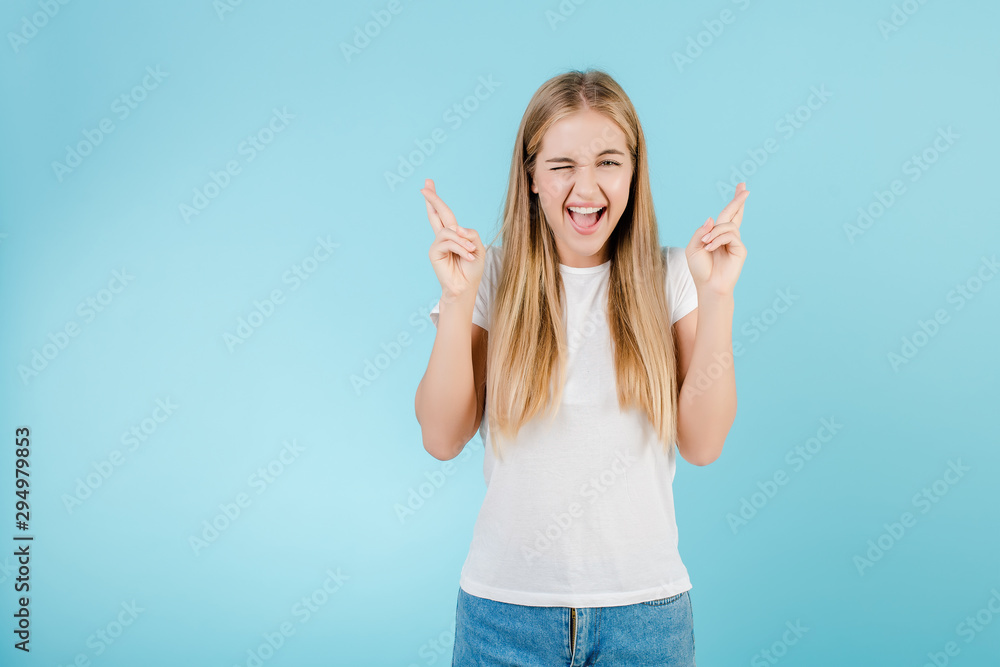 happy young girl with fingers crossed hoping and praying for luck isolated over blue happy young girl with fingers crossed hoping and praying for luck isolated over blue