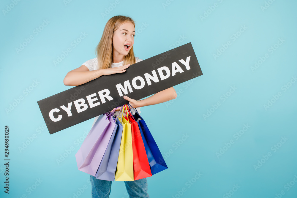 happy woman with cyber monday sign and colorful shopping bags isolated over blue happy woman with cyber monday sign and colorful shopping bags isolated over blue