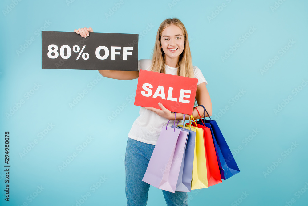 smiling girl with sale 80% off sign and colorful shopping bags isolated over blue smiling girl with sale 80% off sign and colorful shopping bags isolated over blue
