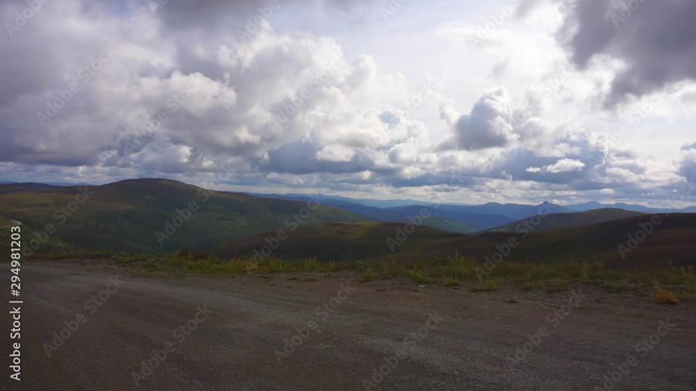 Pan view, driving on the Top of the world highway, overlooking green hills and Alaskan wilderness, on a cloudy day, in Alaska, USA Pan view, driving on the Top of the world highway, overlooking green hills and Alaskan wilderness, on a cloudy day, in Alaska, USA