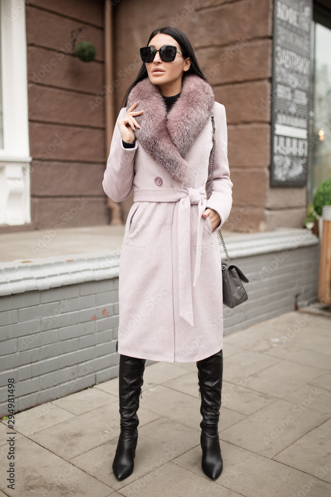 Fashion woman walks around the city. a coat with fur on it. Set of warm clothes
