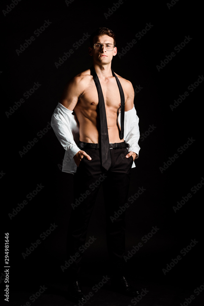 handsome undressed man in glasses standing isolated on black