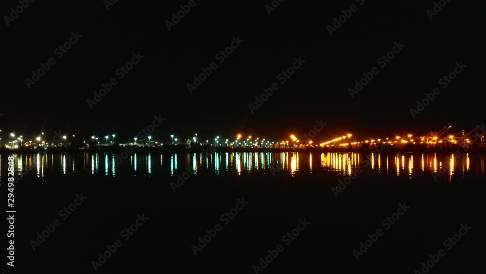 The waves gently sway as the harbor lights reflect across the bay. Early morning just before sunrise. The waves gently sway as the harbor lights reflect across the bay. Early morning just before sunrise.