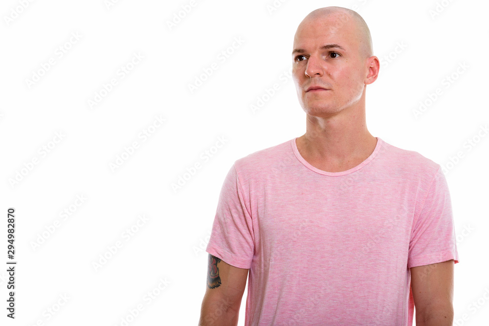 Studio shot of young handsome bald man thinking while looking at Studio shot of young handsome bald man thinking while looking at