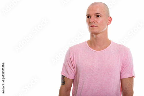 Studio shot of young handsome bald man thinking while looking at