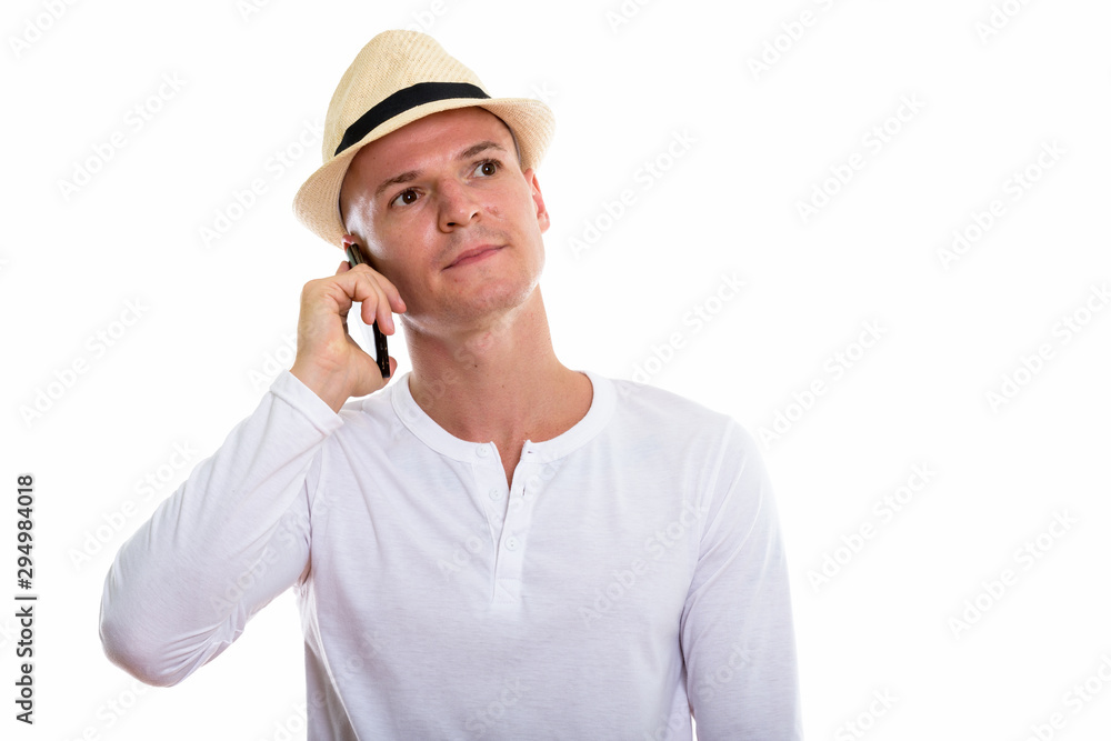 Studio shot of young handsome man talking on mobile phone while Studio shot of young handsome man talking on mobile phone while