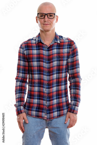 Studio shot of young handsome bald man standing while wearing ey