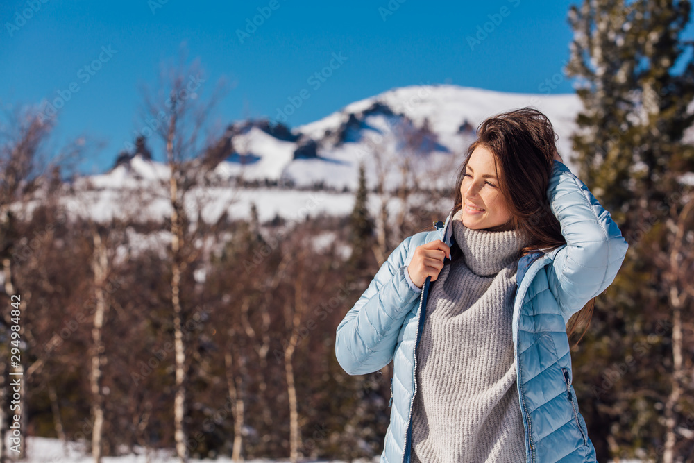 Portrait of a young beautiful brunette woman with blue eyes and freckles on face in winter snowy mountain landscape. Beautiful girl in the winter outdoors. Portrait of a young beautiful brunette woman with blue eyes and freckles on face in winter snowy mountain landscape. Beautiful girl in the winter outdoors.