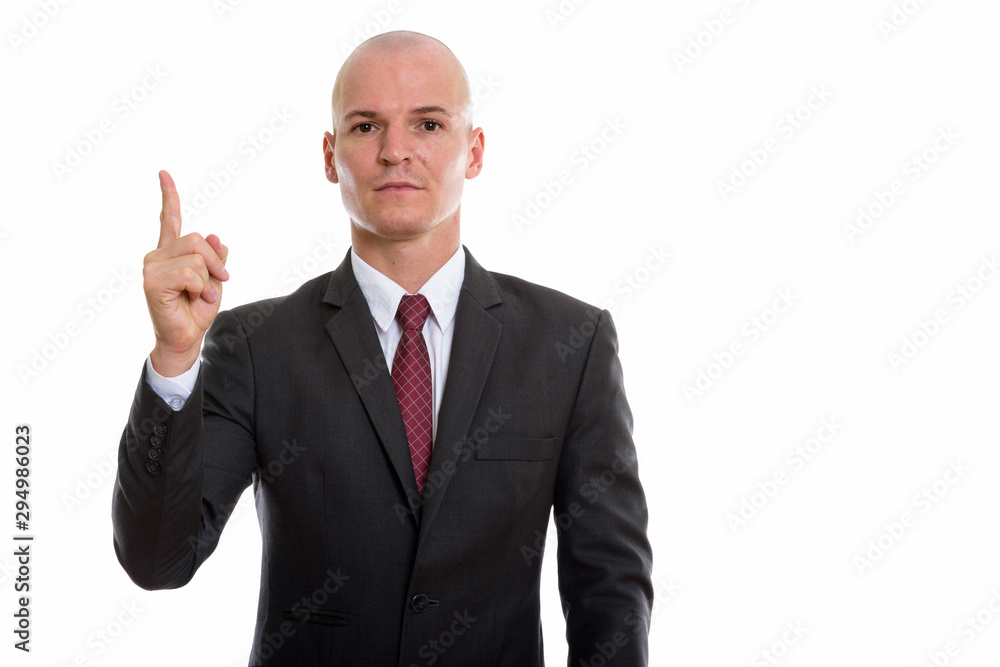 Studio shot of young handsome bald businessman pointing finger u Studio shot of young handsome bald businessman pointing finger u