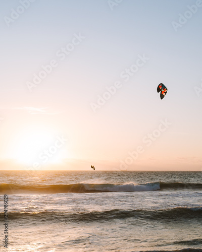 Man kitesurfing at Scarborough Beach as the sun sets over the ocean in the distance. 