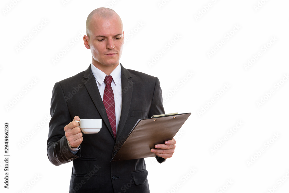 Studio shot of young handsome bald businessman reading on clipbo Studio shot of young handsome bald businessman reading on clipbo