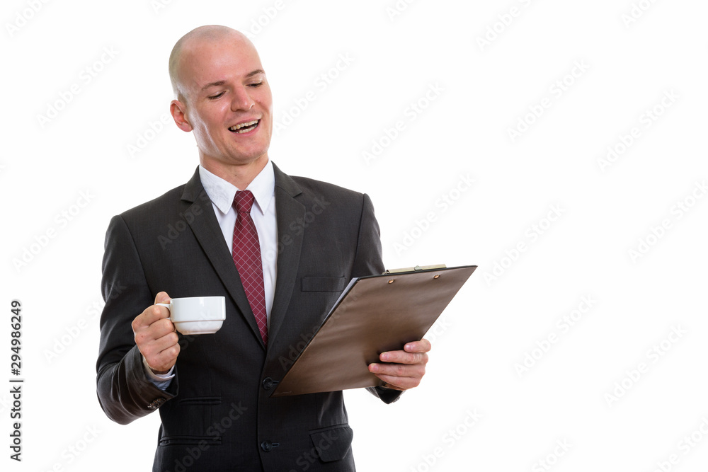 Studio shot of young happy bald businessman smiling and reading Studio shot of young happy bald businessman smiling and reading