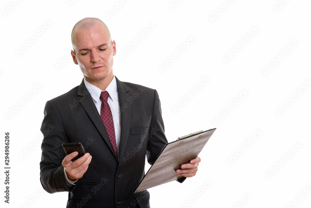 Studio shot of young handsome bald businessman using mobile phon Studio shot of young handsome bald businessman using mobile phon
