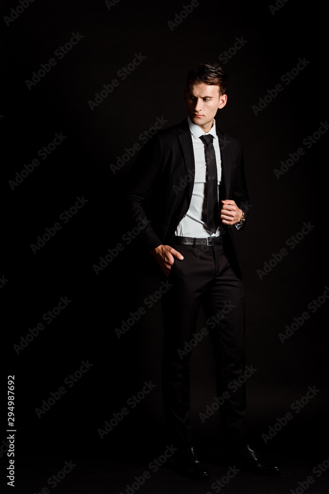 handsome businessman in suit standing with hand in pocket on black handsome businessman in suit standing with hand in pocket on black