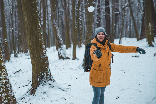 smiling young woman throwing snowball in forest