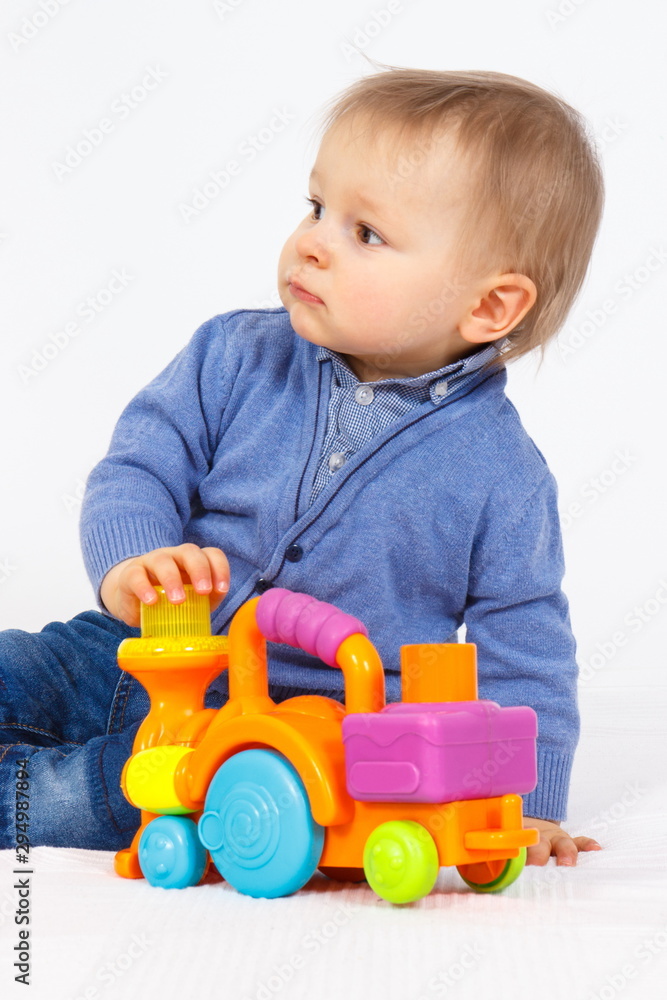 Little baby boy playing with plastic locomotive toy, child development concept Little baby boy playing with plastic locomotive toy, child development concept