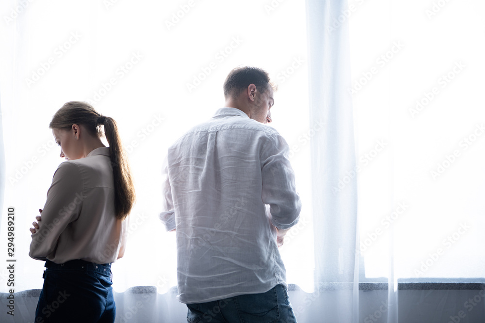 Fototapeta premium upset woman and man in shirts standing near window