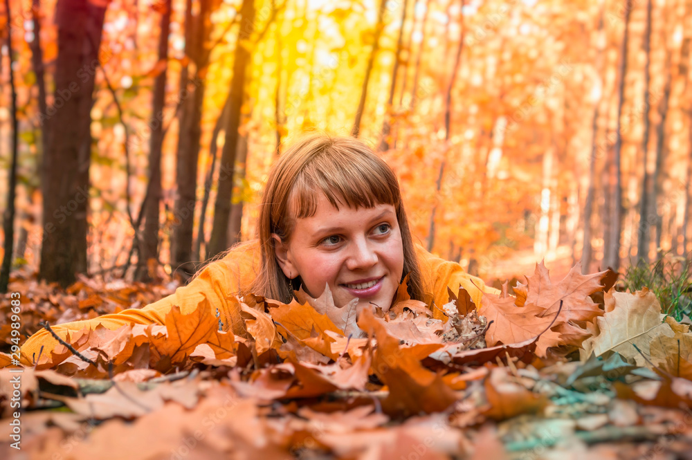 Attractive woman is lying over autumn leaves in park Attractive woman is lying over autumn leaves in park