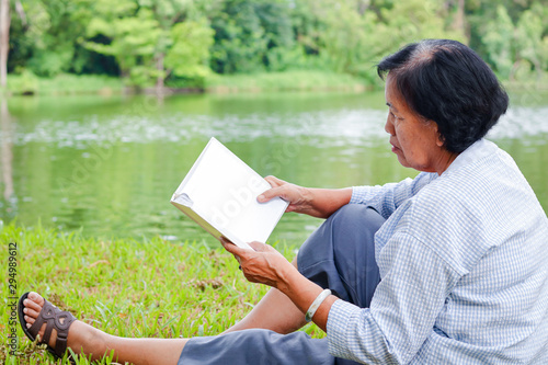 An elderly woman sitting and reading a book in a park Happy life after retirement