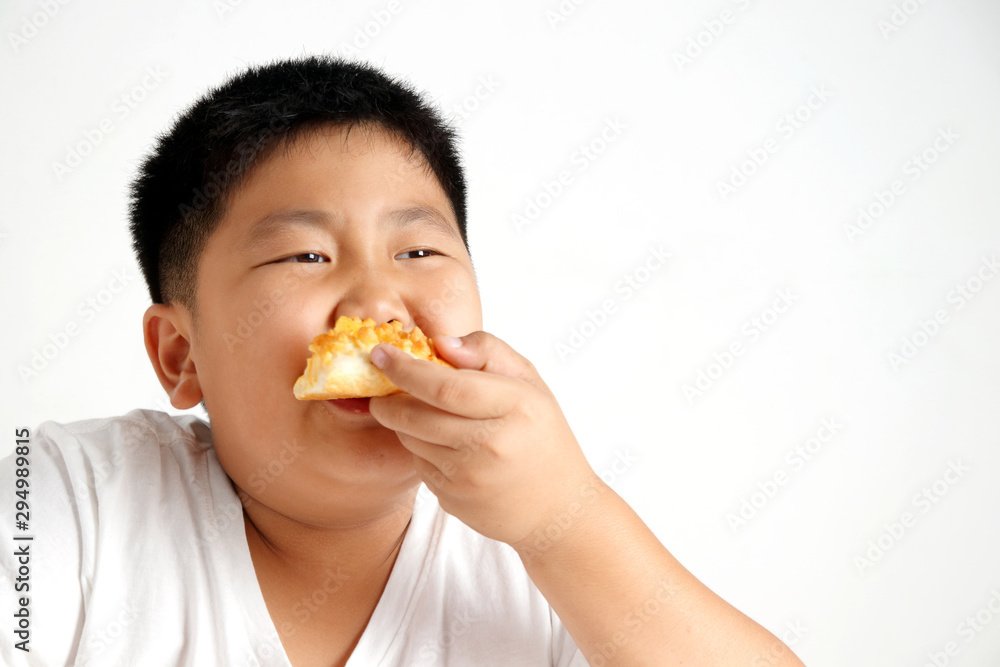 The fat Asian boy is eating a delicious pizza. Concept of eating food for health benefits. White background The fat Asian boy is eating a delicious pizza. Concept of eating food for health benefits. White background