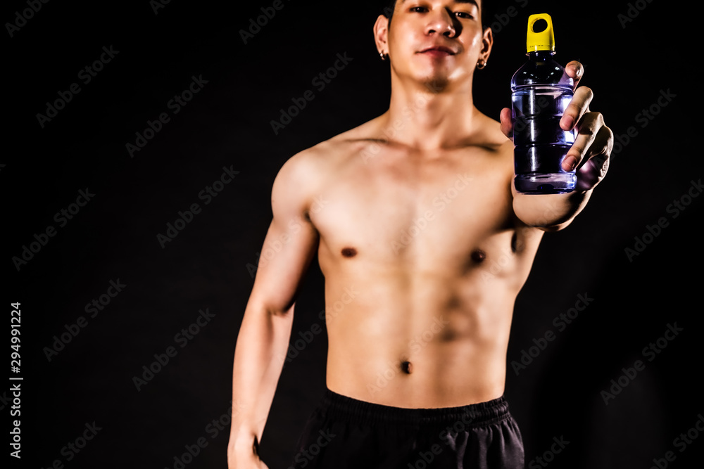 sport man standing holding bottled water and showing muscle bodybuilding on black backgrounds, fitness concept, sport concept