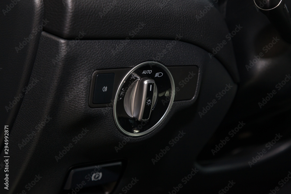 The dashboard of the car's interior is black with a dipped headlamp switch and side lights with a light sensor and automatic dimming and fog light button. Auto service industry.