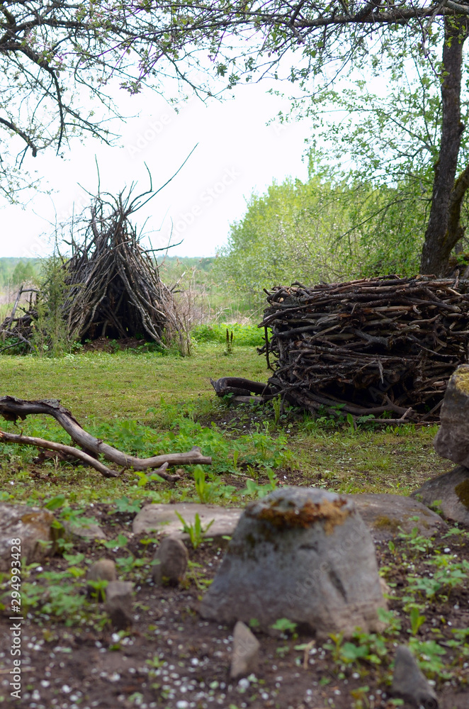 Obraz premium hut and nest of old dry branches as art objects in the garden-an example of the use of garden moussor in landscape design