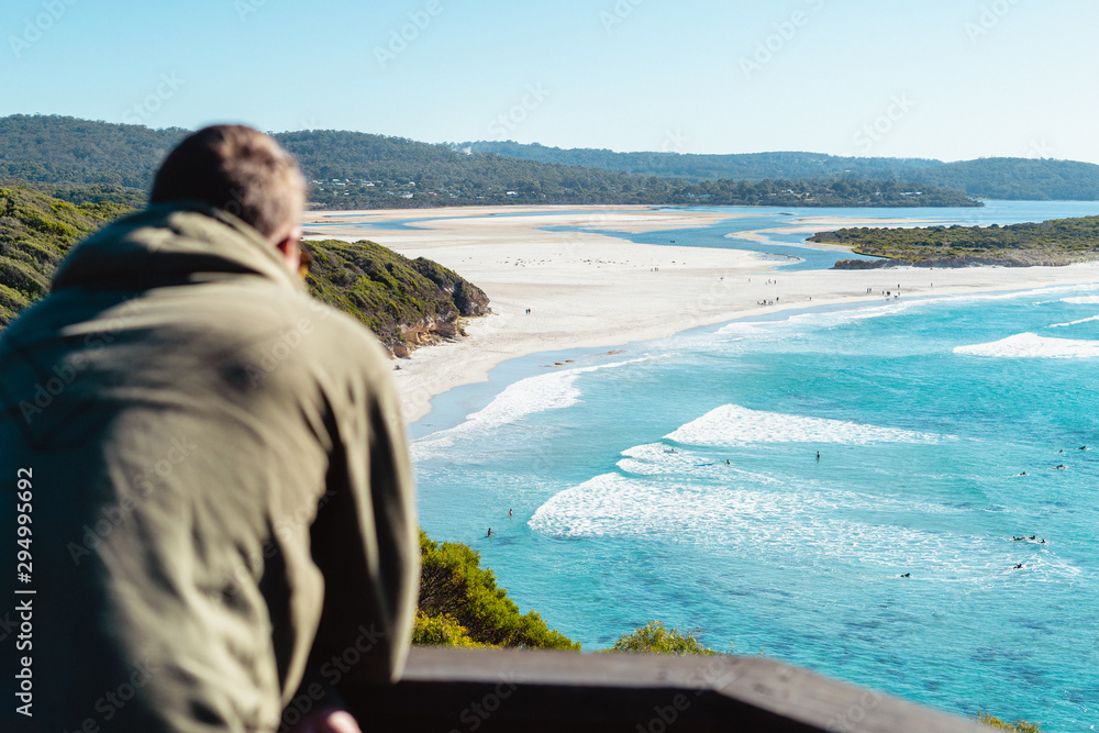 Ocean Beach, Denmark, Australia. Beautiful wide beach with surfers surfing waves in clear blue water. River mouth can be seen in the background with some trees in the foreground.