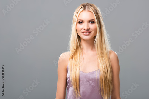 smiling elegant blonde girl in violet satin dress isolated on grey