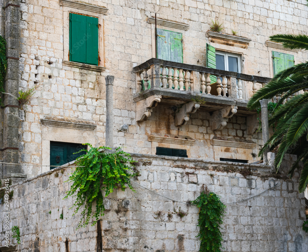 Beautiful details on an old stone house with a beautiful balcony and with green doors and green wooden shutters and overgrown walls, mediterranean architecture, Vis island, Croatia, Europe