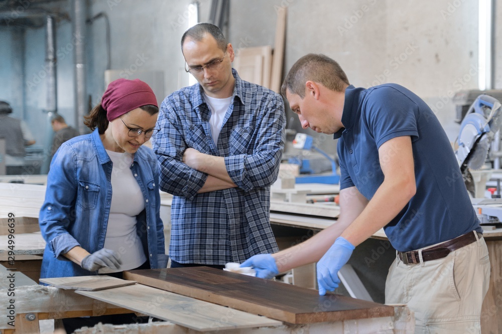 Workers in carpentry woodworking workshop, varnishing wooden plank with oil Workers in carpentry woodworking workshop, varnishing wooden plank with oil