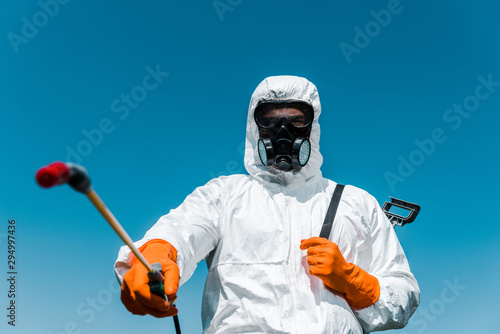 selective focus of exterminator in uniform and latex gloves holding spray outside