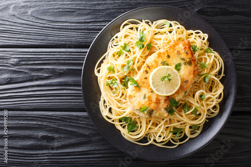 Authentic fried breaded chicken Francaise with spaghetti in lemon wine gravy close-up on a plate. Horizontal top view photo