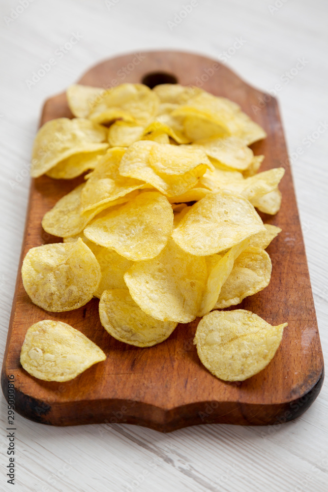 Tasty potato chips with salt on a rustic wooden board, low angle view. Close-up. Tasty potato chips with salt on a rustic wooden board, low angle view. Close-up.