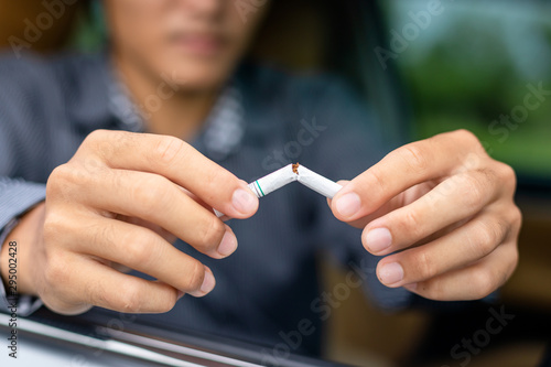 Young man sitting in the car and destroy cigarette by hand. Stop smoking in car concept