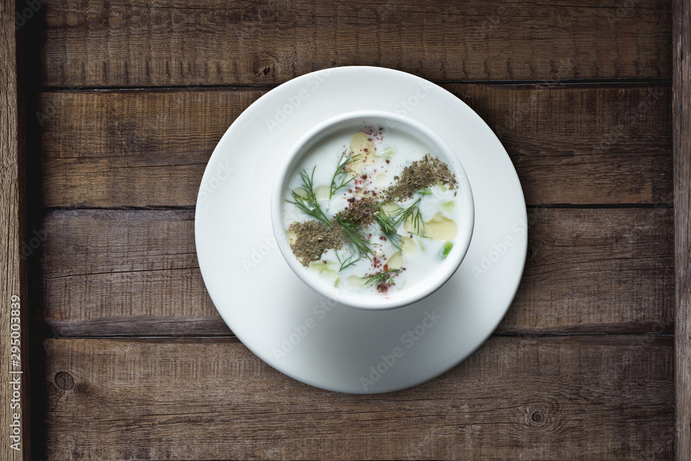 Turkish Yayla or yogurt soup with mint sauce (Tzatziki) isolated on rustic wooden table Turkish Yayla or yogurt soup with mint sauce (Tzatziki) isolated on rustic wooden table