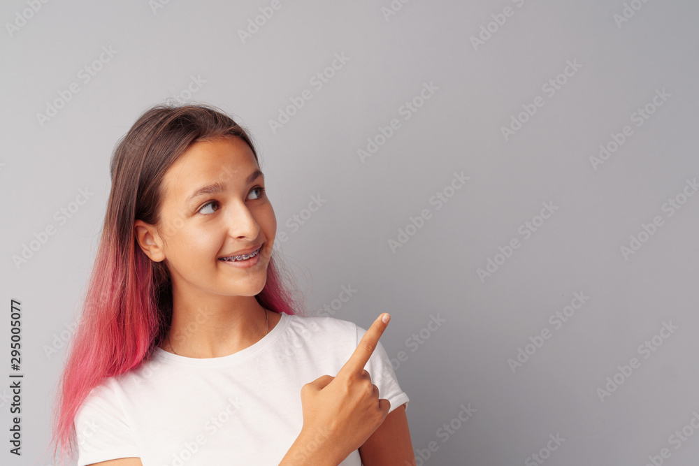 Smiling casual teen girlpointing finger at copy space. Smiling casual teen girlpointing finger at copy space.