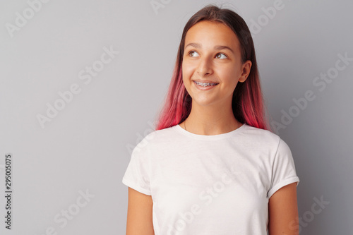 Young girl teenager with pink hair happy and smiling over gray background photo