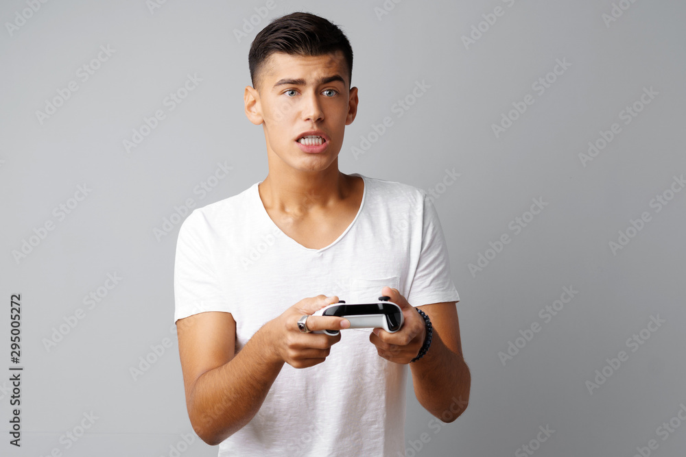 Young teen man playing with console joystick over a gray background Young teen man playing with console joystick over a gray background