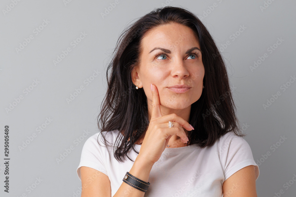 Image of thinking young woman standing over a gray background. Image of thinking young woman standing over a gray background.