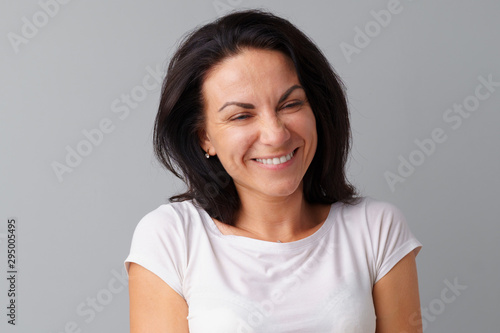 Portrait of joyful brunette young cute woman laughing over a gray background