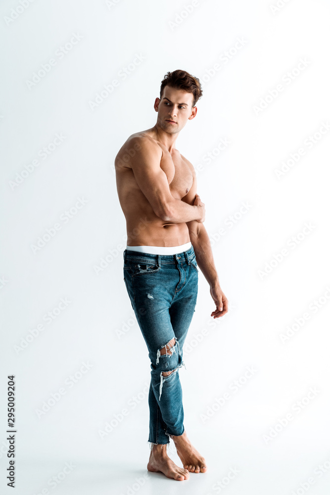 sexy man in jeans touching hand while standing on white sexy man in jeans touching hand while standing on white