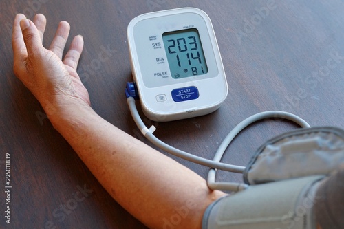 Old Man check blood pressure and heart rate at home with digital pressure very high blood pressure test results.Hypertensive urgency.Need some medicine.Health and Medical concept. photo