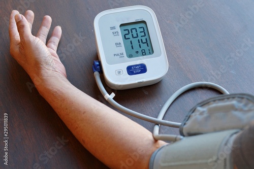 Valokuva Old Man check blood pressure and heart rate at home with digital pressure very high blood pressure test results