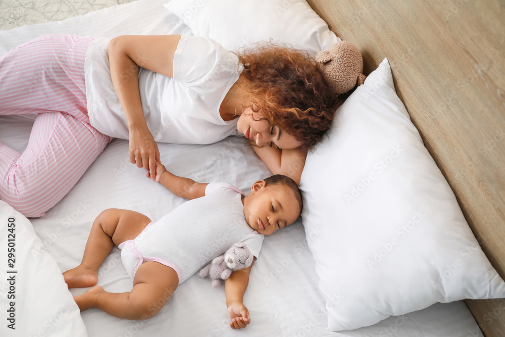 Young African-American woman and her baby sleeping on bed Young African-American woman and her baby sleeping on bed