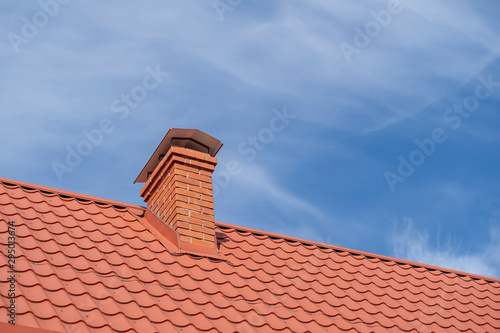 Fotografering Red roof of a detached house and chimney against the blue sky, closeup