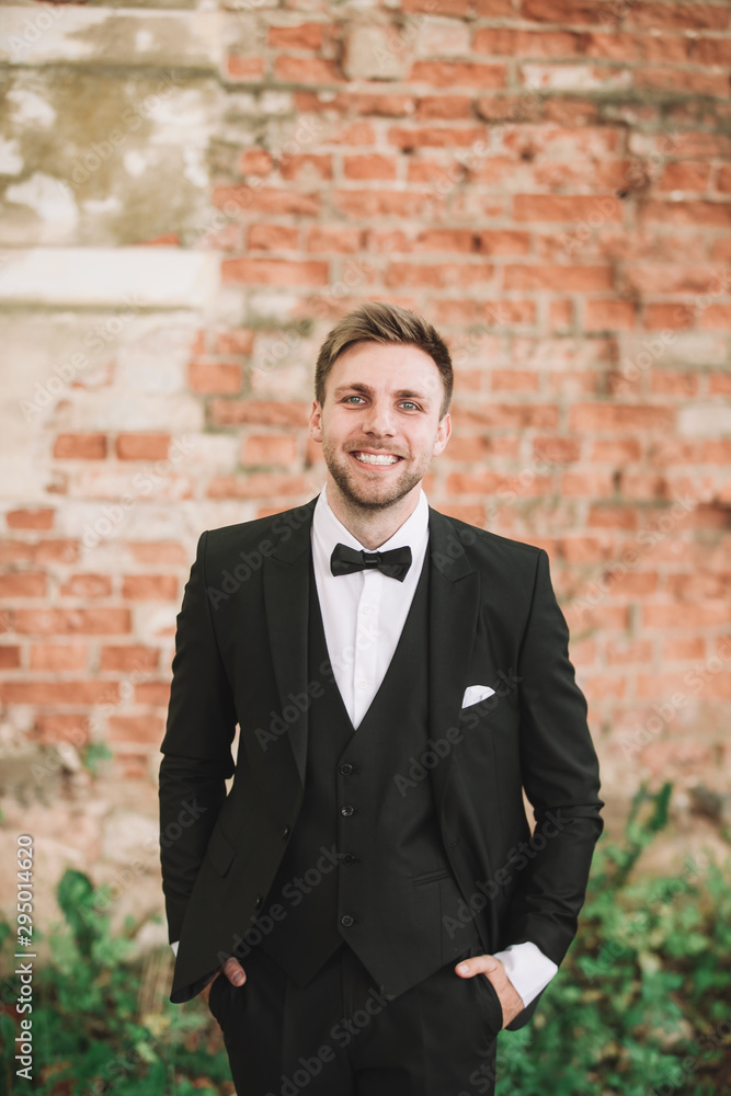e smiling groom in the background of old brick wall. e smiling groom in the background of old brick wall.